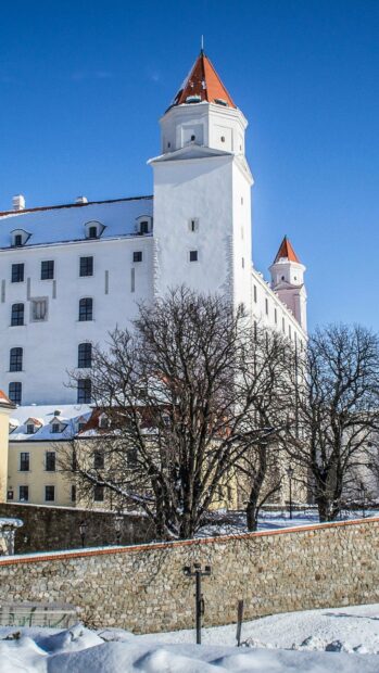 A snowy scene features Bratislava castle with clear blue sky in winter, HD Mobile Wallpaper