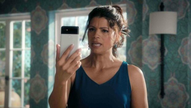 A woman in a blue top looks at her phone with concern in a decorated room, HD Desktop Wallpaper