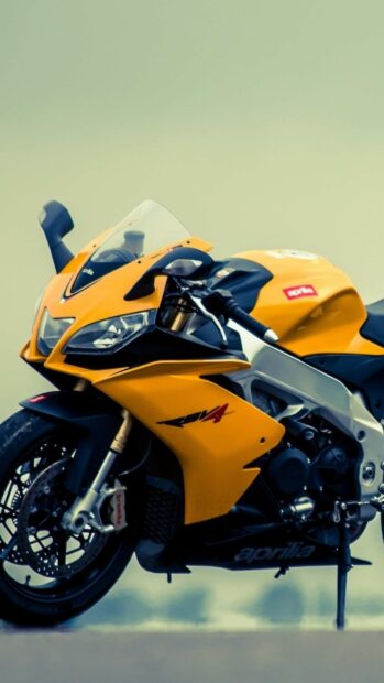 The Aprilia Wallpapers show a close up view of a yellow sport motorcycle parked on a smooth surface, HD Mobile Wallpaper