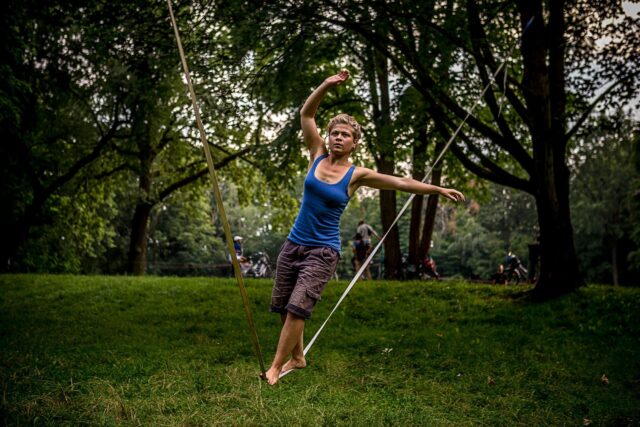Young woman balancing on slackline in lush green park nature slacklining wallpapers