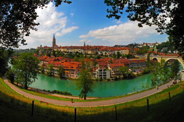 The Aare River flows through a historic Swiss town with red rooftops, 2K Desktop Wallpaper