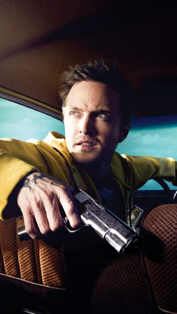 Aaron Paul is holding a gun inside a car while looking tense and alert, 2K Phone Wallpaper