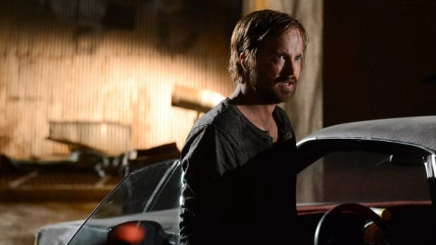 Aaron Paul stands near a car in a dimly lit area showing a serious expression, 4K Desktop Wallpaper