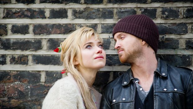 Aaron Paul looking closely at a woman with blonde hair leaning against a brick wall, 4K Desktop Wallpaper
