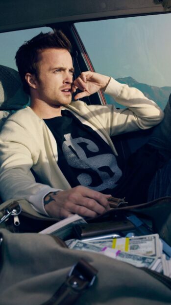 Aaron Paul wallpapers shows him sitting thoughtfully inside a car with money visible, 2K Mobile Wallpaper