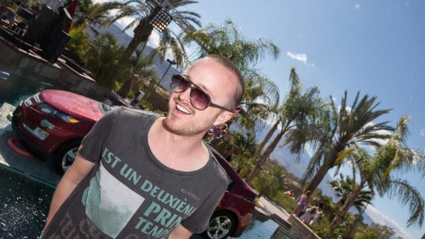 Aaron Paul is smiling wearing sunglasses near a pool and palm trees, HD Desktop Wallpaper
