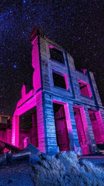 An abandoned building glows with pink and blue lights under a starry night sky featuring the ghost town, HD Phone Wallpaper