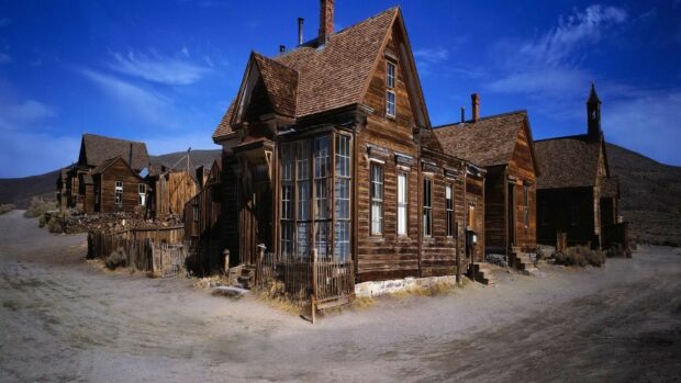 An old deserted ghost town shows weathered wooden buildings under a clear blue sky, HD Desktop Wallpaper