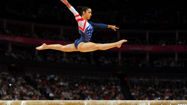 A female gymnast performs a split leap during an acrobatic gymnastics event, HD Desktop Wallpaper