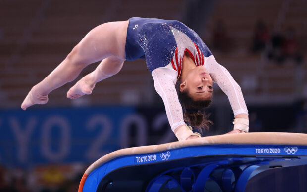 A female acrobatic gymnast is vaulting over equipment during a competition, 2K Desktop Wallpaper