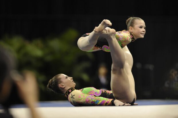 Two athletes perform an acrobatic gymnastics balance routine in vibrant costumes, 2K Desktop Wallpaper