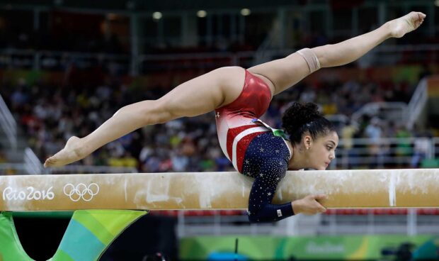 A gymnast performs a balance routine on the beam during a competition with great skill, HD Desktop Wallpaper