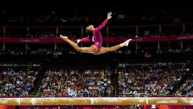 A gymnast performs a split leap during an acrobatic gymnastics event, HD Desktop Wallpaper