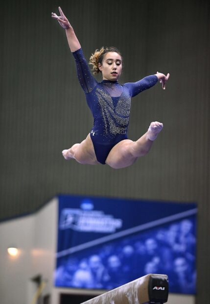 A gymnast performs an acrobatic gymnastics leap on the balance beam, HD Desktop Wallpaper