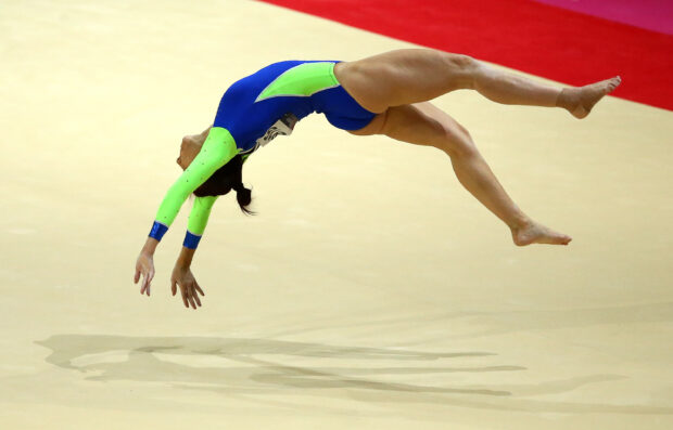 A gymnast performs a mid air flip in acrobatic gymnastics wearing a blue and green leotard, 2K Desktop Wallpaper