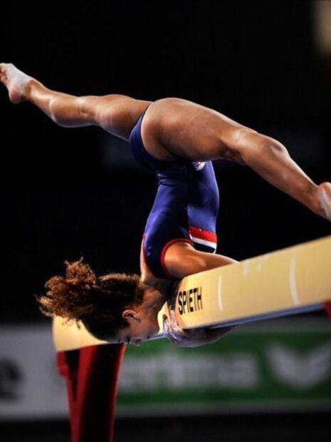 A gymnast performs an acrobatic move on the balance beam, HD Mobile Wallpaper
