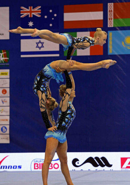 A team of acrobatic gymnasts in blue outfits performing a balance stunt during a competition, HD Desktop Wallpaper