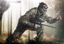 A paintball player is crouching and moving cautiously in a forest setting wearing camouflage clothing, HD Desktop Wallpaper