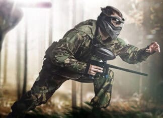 A paintball player is crouching and moving cautiously in a forest setting wearing camouflage clothing, HD Desktop Wallpaper