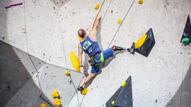 A man with a prosthetic leg is climbing an indoor rock wall during a competition using rock climbing wallpapers, HD Desktop Wallpaper