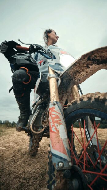 A rider on an enduro motorbike rides through a muddy trail in the wilderness, 4K Phone Wallpaper