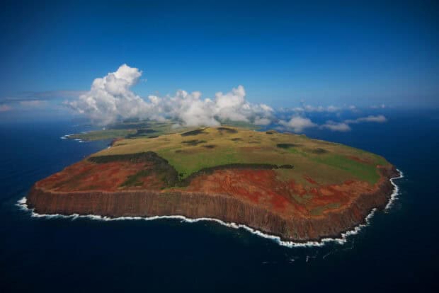 Aerial view shows Easter Island’s rugged coastline and volcanic landscape under a blue sky, HD Desktop Wallpaper