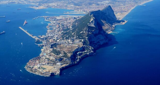 A detailed aerial view of the Rock of Gibraltar surrounded by the sea and cityscape nearby, 2K Desktop Wallpaper