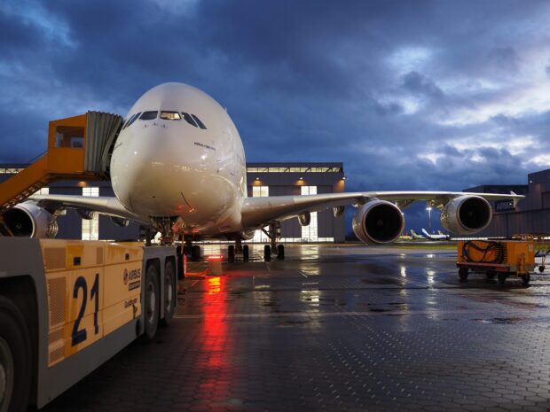 Airbus A380 is parked on the tarmac in front of a hangar at dusk, 2K Desktop Wallpaper