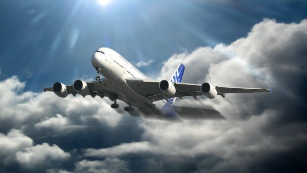 An Airbus A380 is flying high above thick clouds with sunlight breaking through, HD Desktop Wallpaper