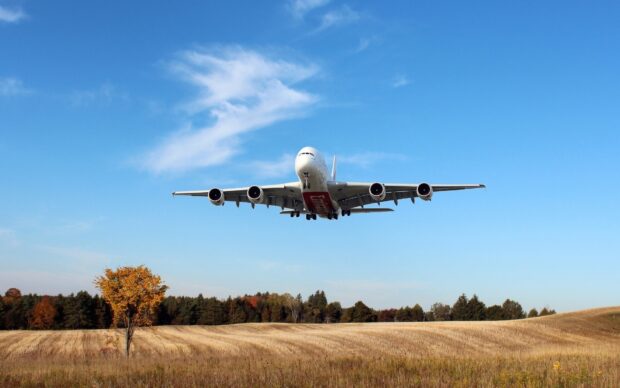 An Airbus A380 is flying low over a golden field with clear blue skies, HD Desktop Wallpaper
