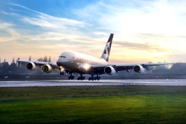 An Airbus A380 is landing on a runway with its lights on during sunset, HD Desktop Wallpaper