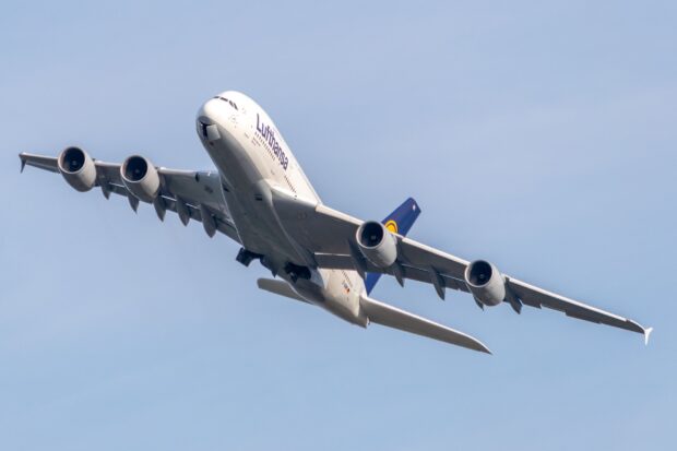 An Airbus A380 is shown flying with its landing gear retracting against a clear blue sky, 2K Desktop Wallpaper