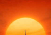 An aircraft is flying toward a pier with the sun setting in the background, 2K Mobile Wallpaper