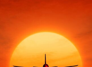 An aircraft is flying toward a pier with the sun setting in the background, 2K Mobile Wallpaper