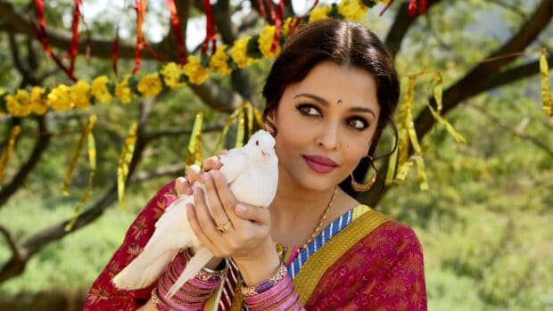 Aishwarya Rai gently holding a white dove with trees and flowers in the background, HD Desktop Wallpaper