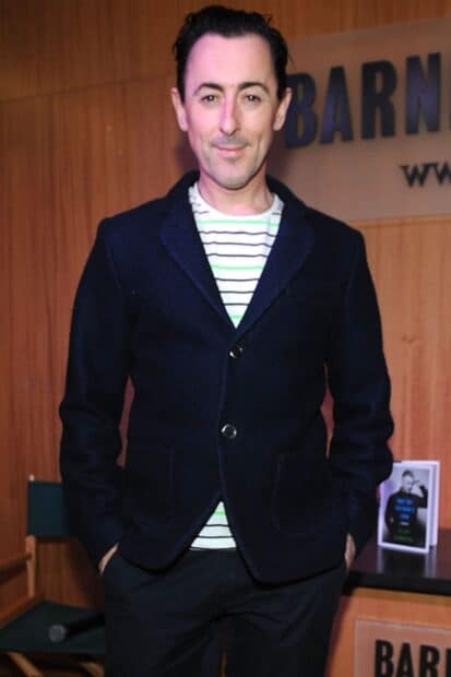 Alan Cumming wallpapers shows a man wearing a dark blazer with hands in pockets indoors, HD Mobile Wallpaper