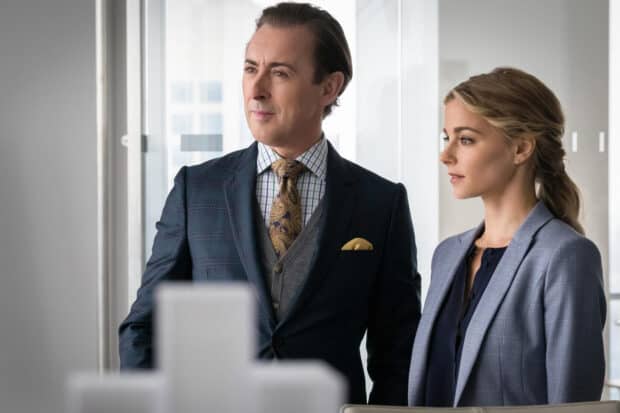 Alan Cumming stands beside a woman in an office setting showing confidence, HD Desktop Wallpaper