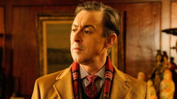 Alan Cumming wallpapers show him wearing a brown coat and red scarf indoors, HD Desktop Wallpaper