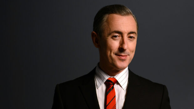 Alan Cumming is wearing a black suit with a red striped tie and smiling, HD Desktop Wallpaper