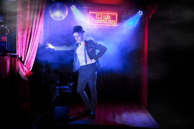 Alan Cumming wallpapers shows a performer in striped suit and bowler hat under colorful lights, HD Desktop Wallpaper