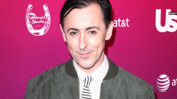 Alan Cumming poses in front of a pink backdrop wearing a green jacket and striped tie, HD Desktop Wallpaper