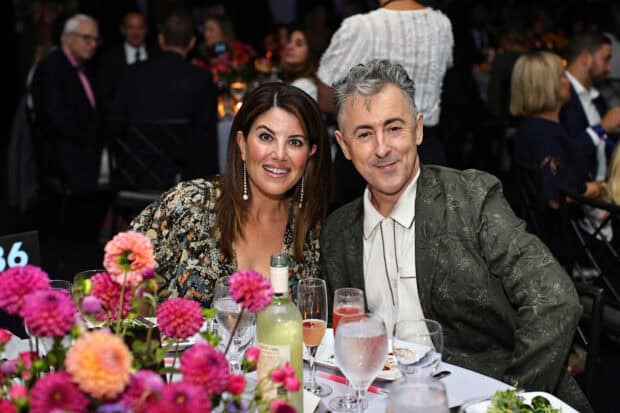 Alan Cumming is sitting next to a woman at a formal dinner table with flowers and drinks, HD Desktop Wallpaper