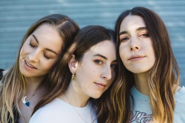 Alana Haim and her sisters posing closely with gentle expressions in natural light, HD Desktop Wallpaper