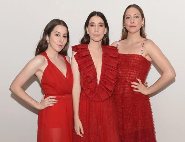 Alana Haim and her sisters pose together wearing elegant red dresses, HD Desktop Wallpaper