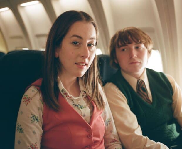 Alana Haim is sitting next to a young man inside an airplane cabin, HD Desktop Wallpaper