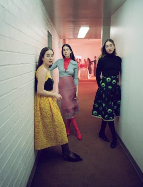 Alana Haim and others stand in a hallway wearing colorful dresses, HD Desktop Wallpaper