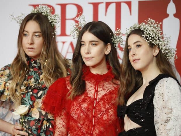 Alana Haim poses with two women wearing flower crowns and elegant dresses at an event, HD Desktop Wallpaper