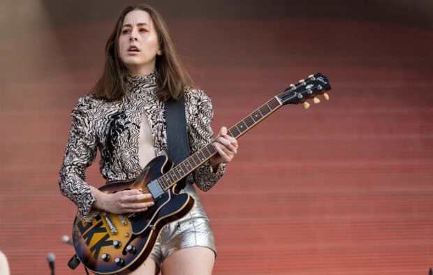 Alana Haim is performing live with an electric guitar on an outdoor stage, HD Desktop Wallpaper