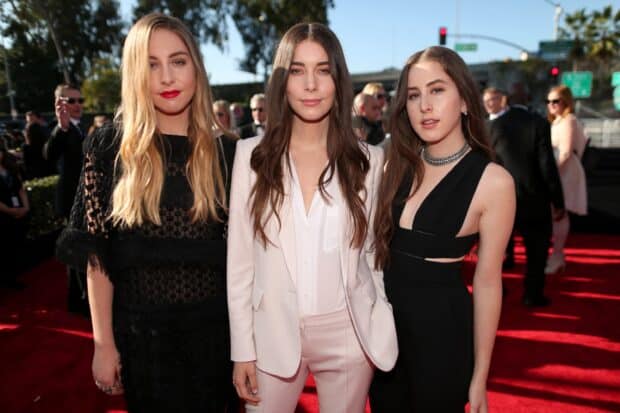 Alana Haim with her sisters posing together at a formal outdoor event, 2K Desktop Wallpaper