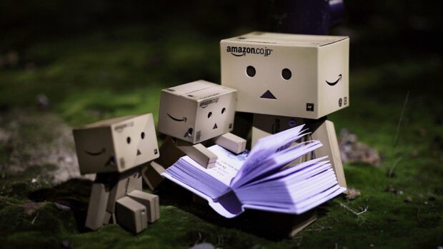 Three Amazon cardboard figures reading an open book outdoors at night with mossy ground, HD Desktop Wallpaper